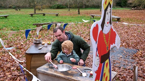 Alice's Christmas in Wonderland at Polesden Lacey 2025: a young boy and his father play with a pretend kitchen in the Tiny Wonderland outdoor play area